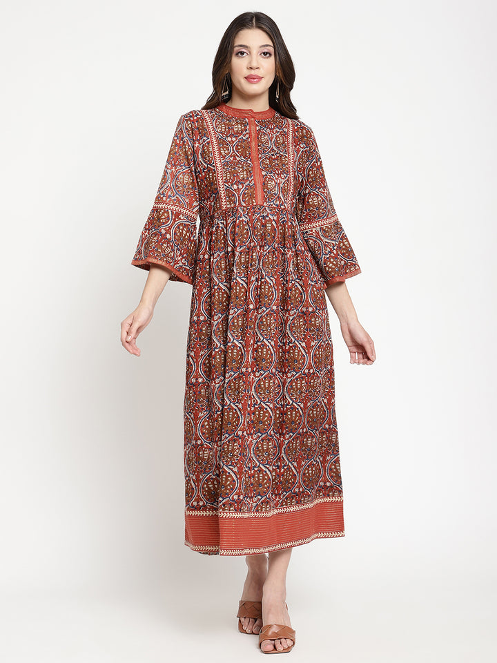 Woman posing in a rust flared dress against a white background.