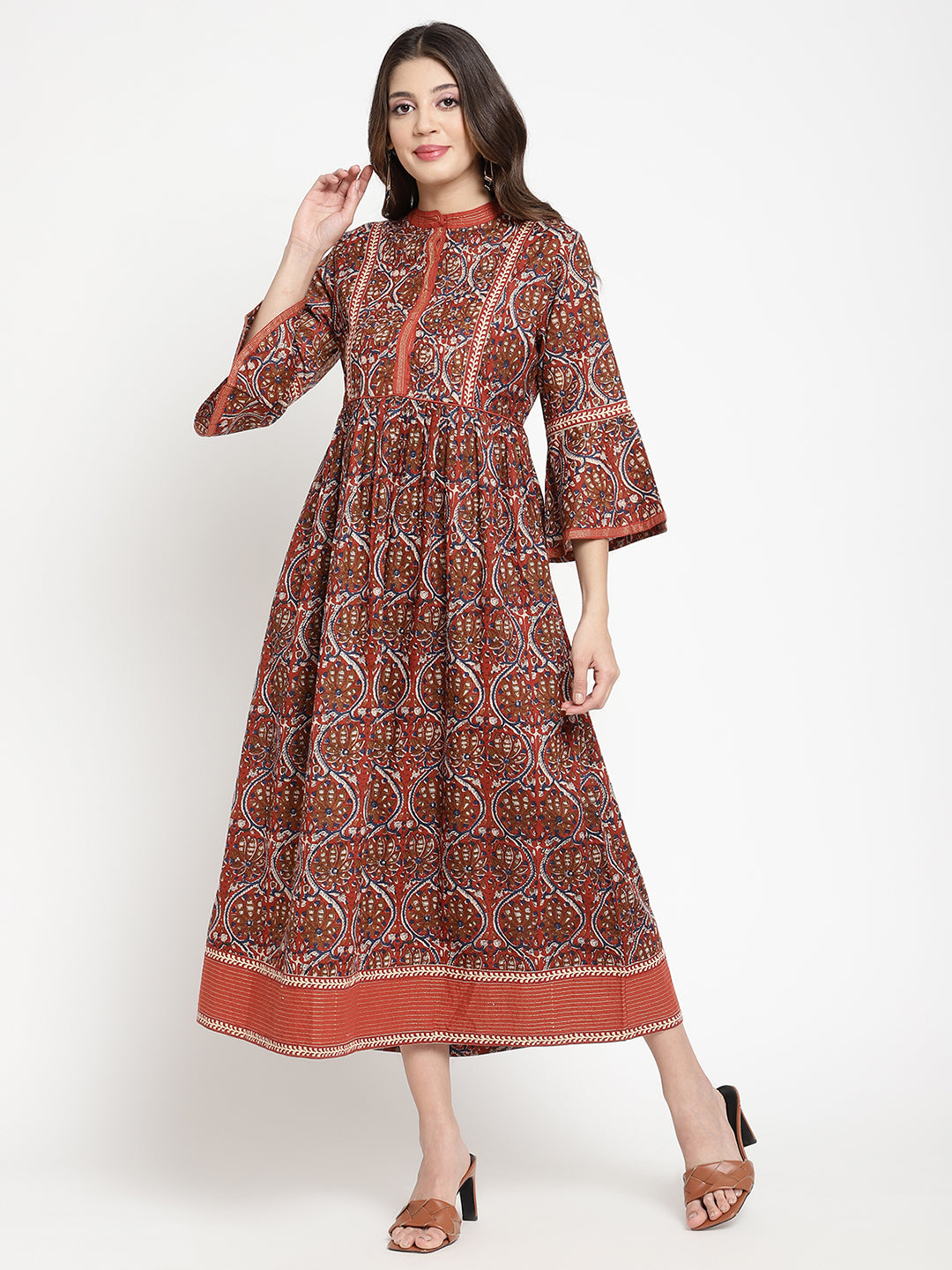 Woman posing in a rust flared dress against a white background.