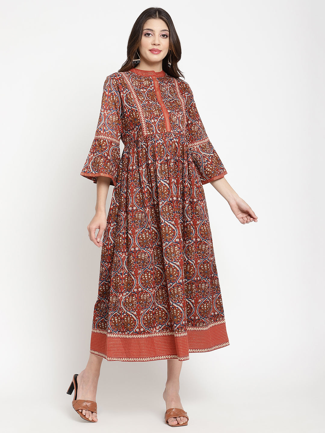 Woman posing in a rust flared dress against a white background.