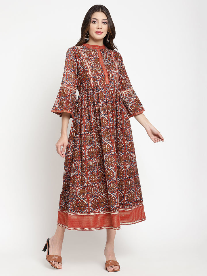 Woman posing in a rust flared dress against a white background.