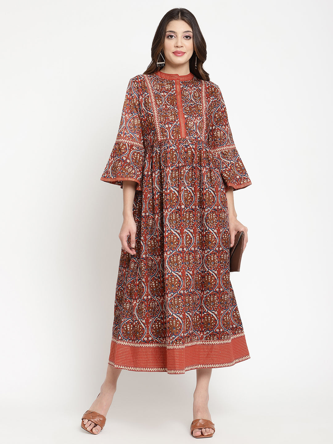 Woman posing in a rust flared dress against a white background.