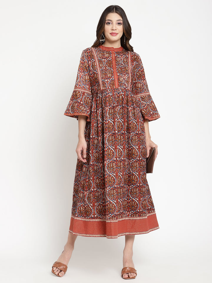 Woman posing in a rust flared dress against a white background.